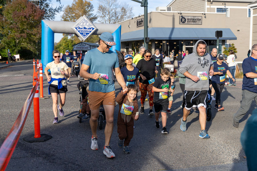 A father starts the Run for Warmth with an adorable youngster wearing a bear suit. Other young racers are also with parents.