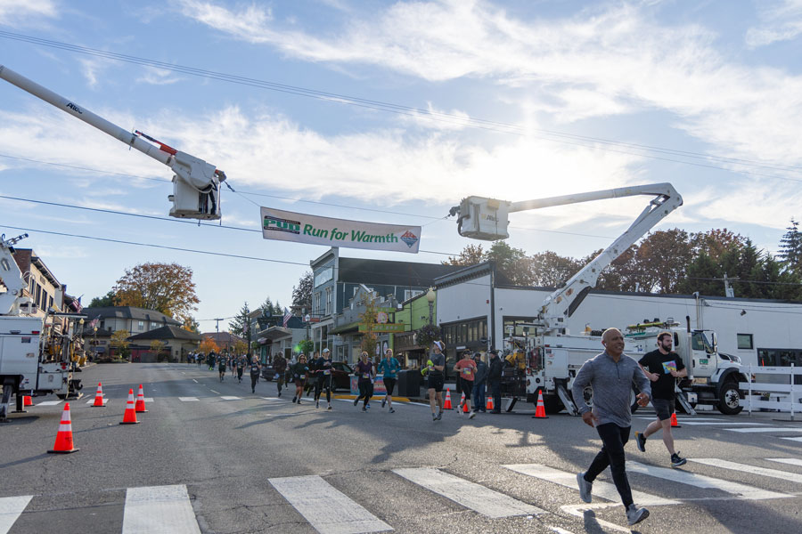 Morning light casts a lovely glow on First Street and the Run for Warmth signs between two bucket trucks.