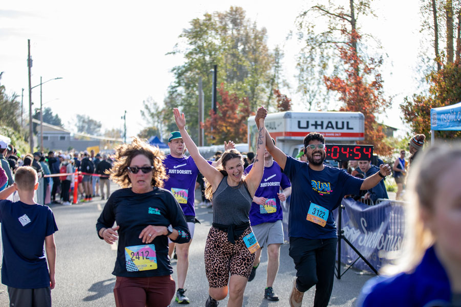 Excited finishers hold up their arms and smile as they finish the Run for Warmth