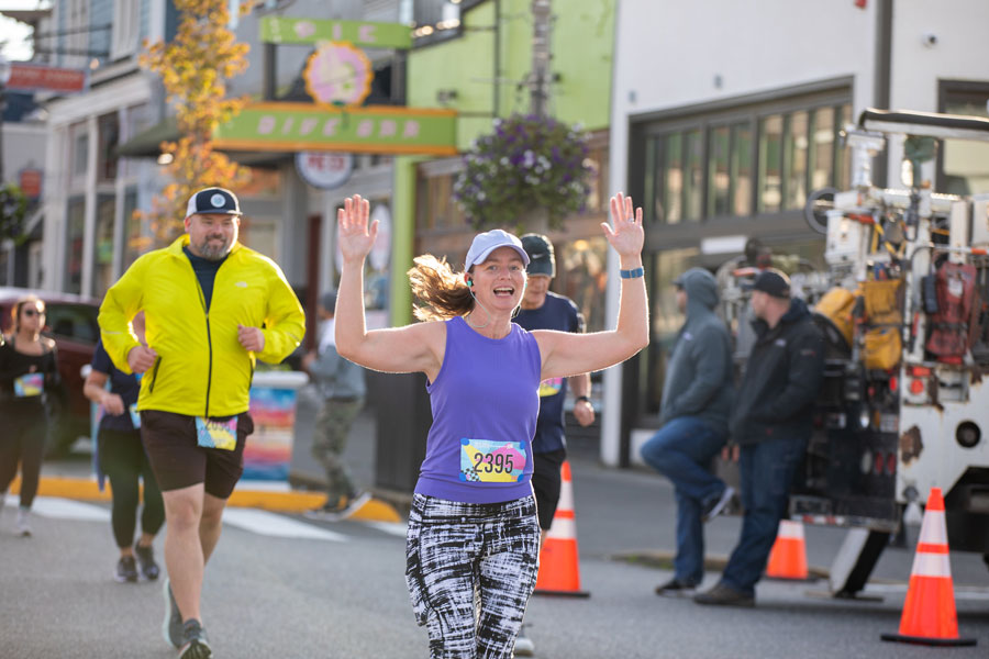 A runner dressed in purple raises her arms in celebration during the Run for Warmth