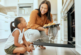 Mother and daughter smiling as cupcakes come out of the oven